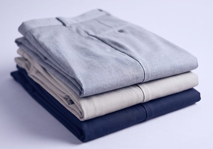 Stack of folded formal trousers in grey, stone and navy
