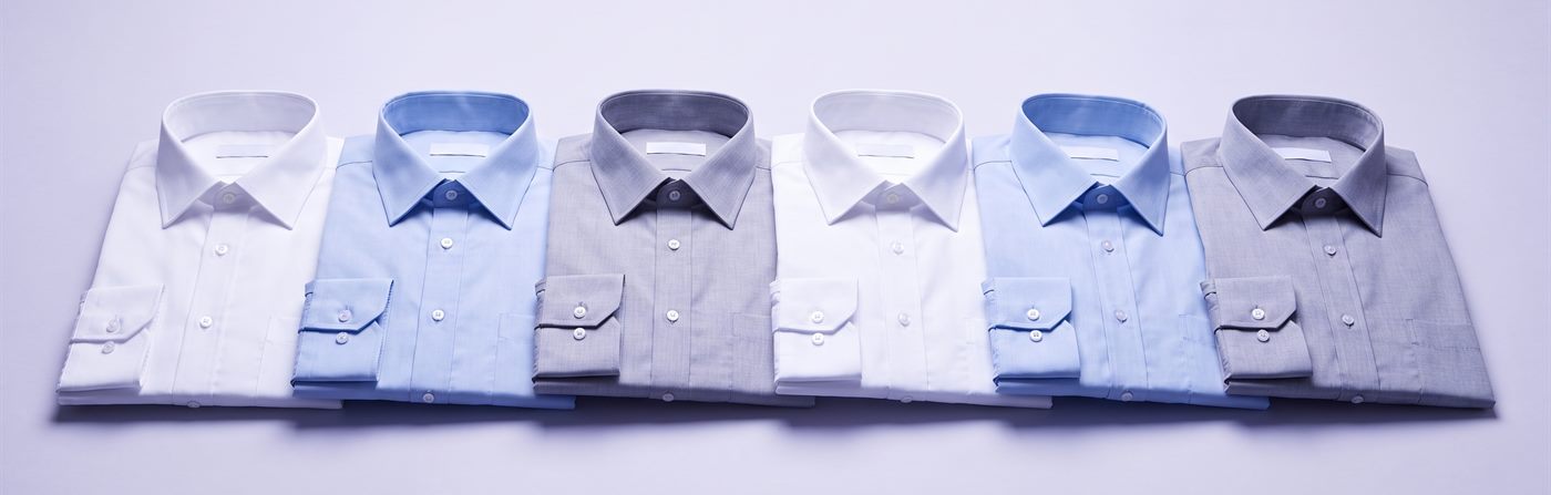 Folded woven dress shirts in white, pale blue and grey, collars and cuffs pressed